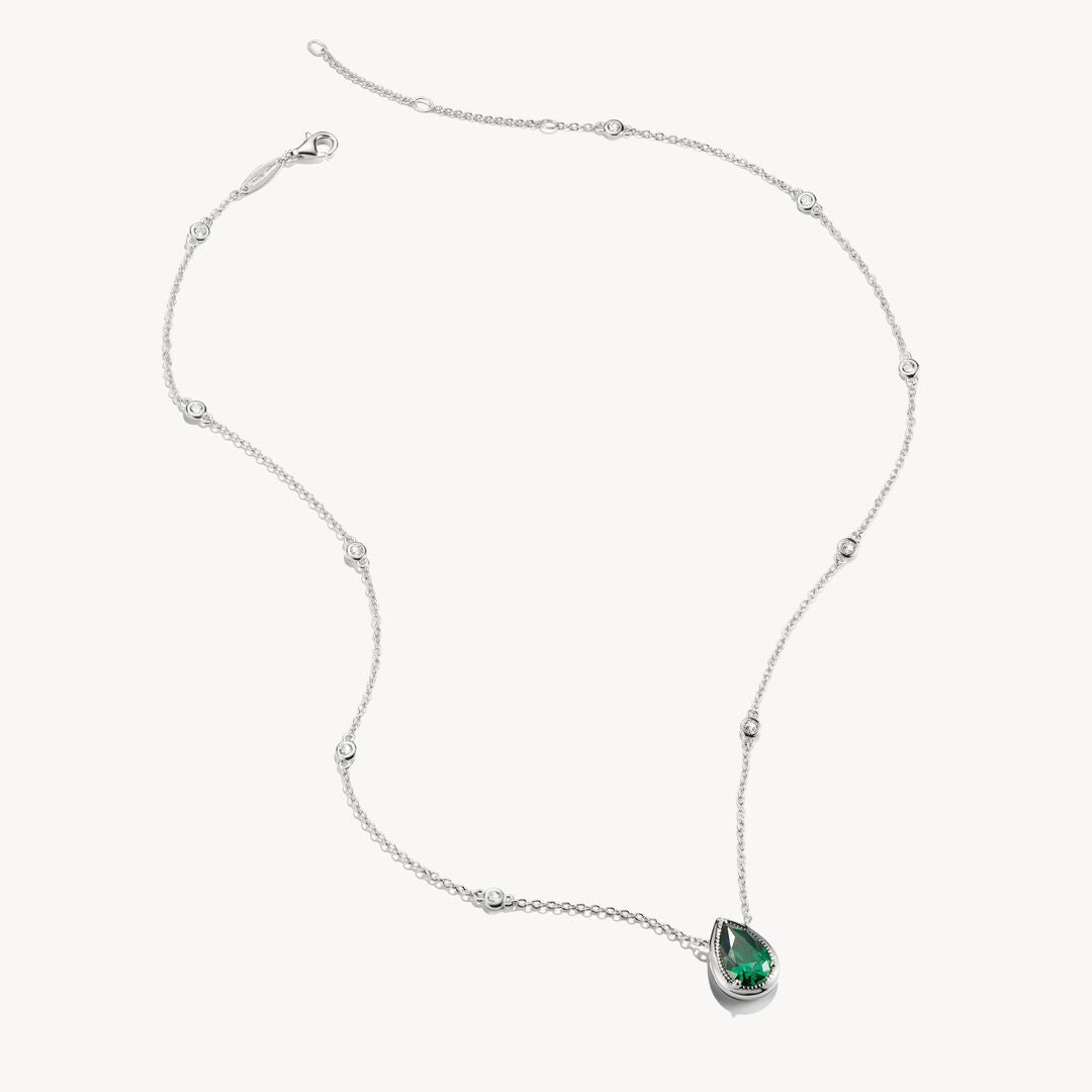 Silver necklace with a green teardrop pendant on a white background