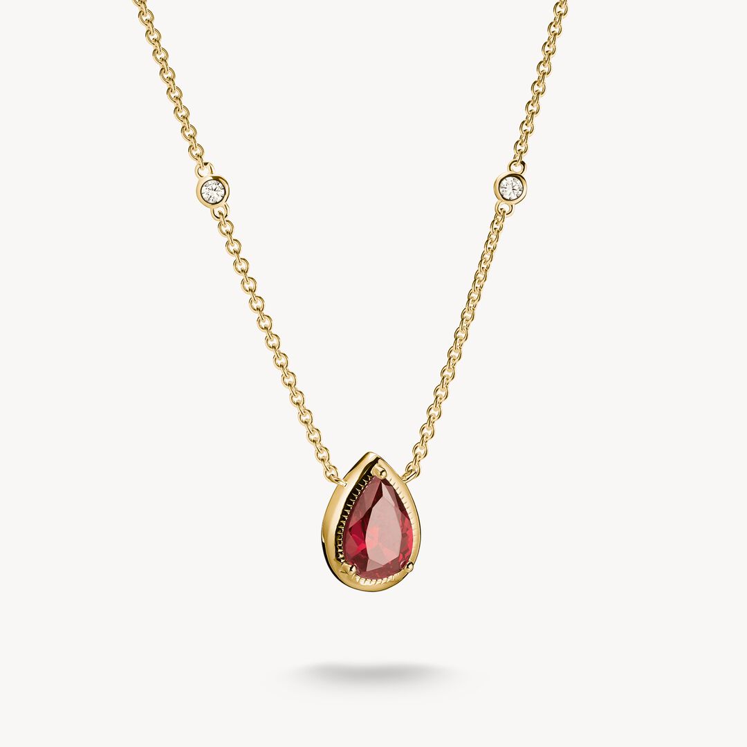 Gold necklace with a red teardrop pendant on a white background