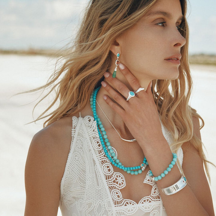 Woman wearing turquoise jewelry on a beach