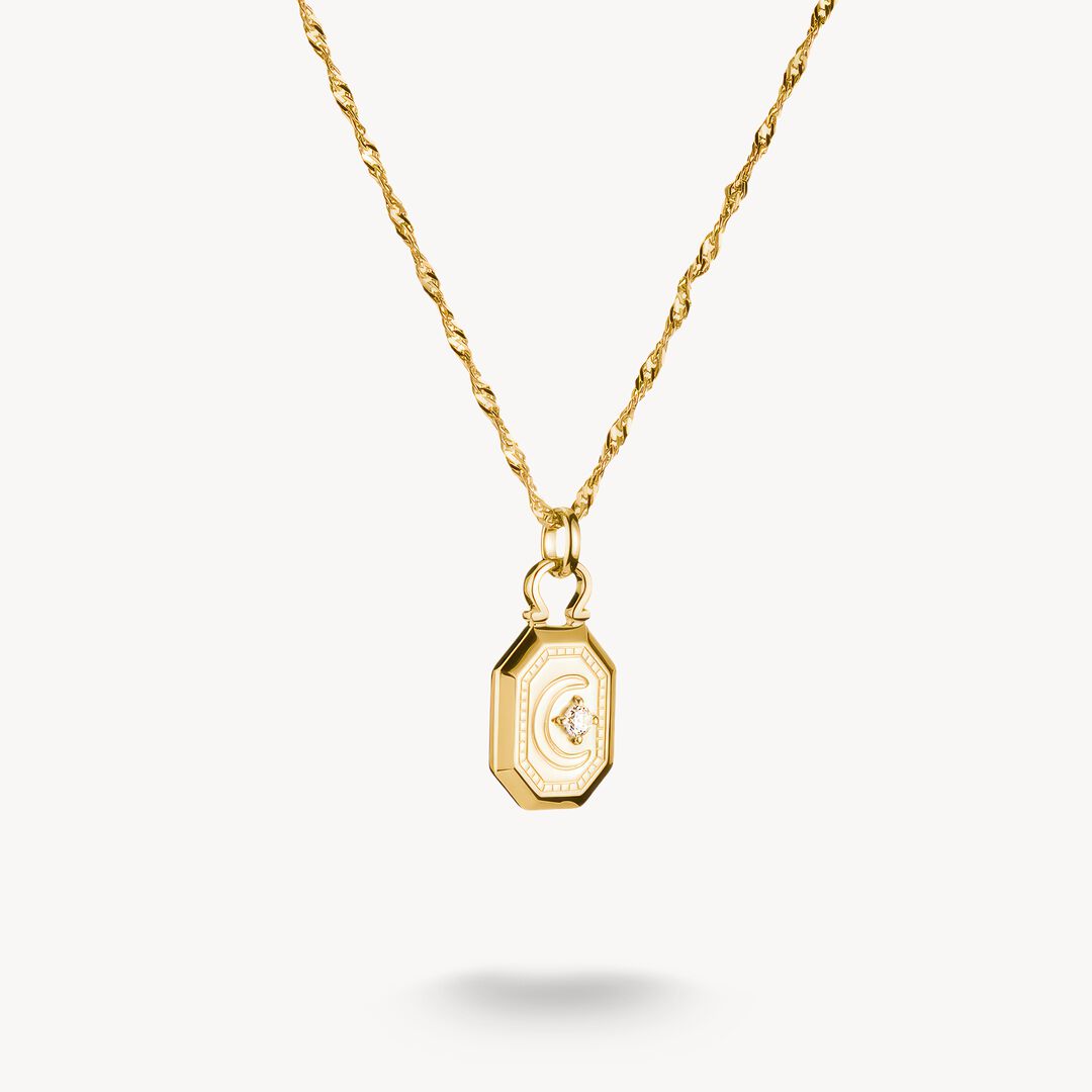Gold necklace with a hexagonal pendant on a white background