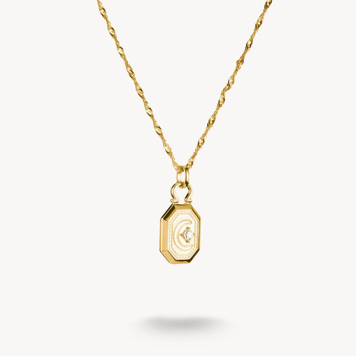 Gold necklace with a hexagonal pendant on a white background
