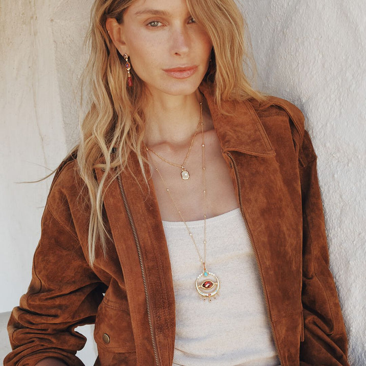 Woman wearing a brown suede jacket with a plain background