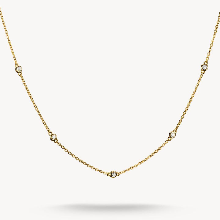 Gold necklace with small diamonds on a light gray background
