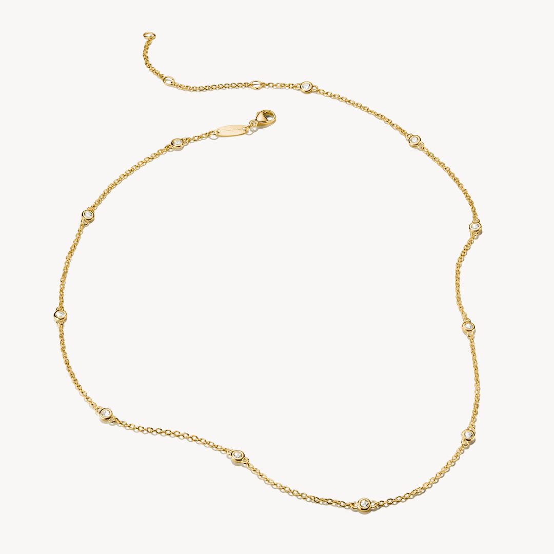 Gold necklace with small diamonds on a light gray background