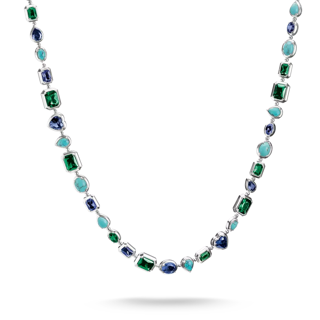 A silver-toned necklace featuring a series of colorful gemstones, including emerald-cut green, oval blue, round turquoise, and marquise-cut light blue stones, displayed against a clean white background.