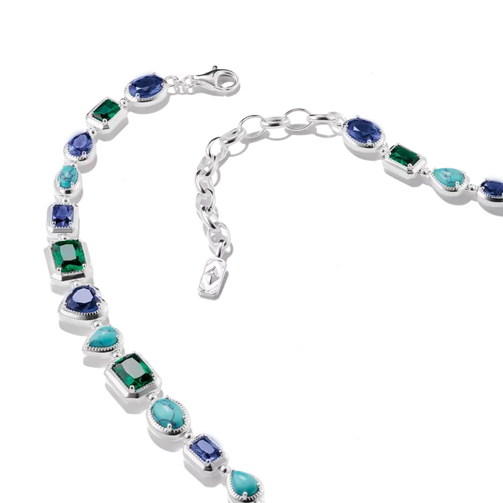 A sterling silver bracelet featuring a variety of colored gemstones, including emerald-cut green, marquise-cut turquoise, round blue, and oval purple stones, displayed on a clean white background.
