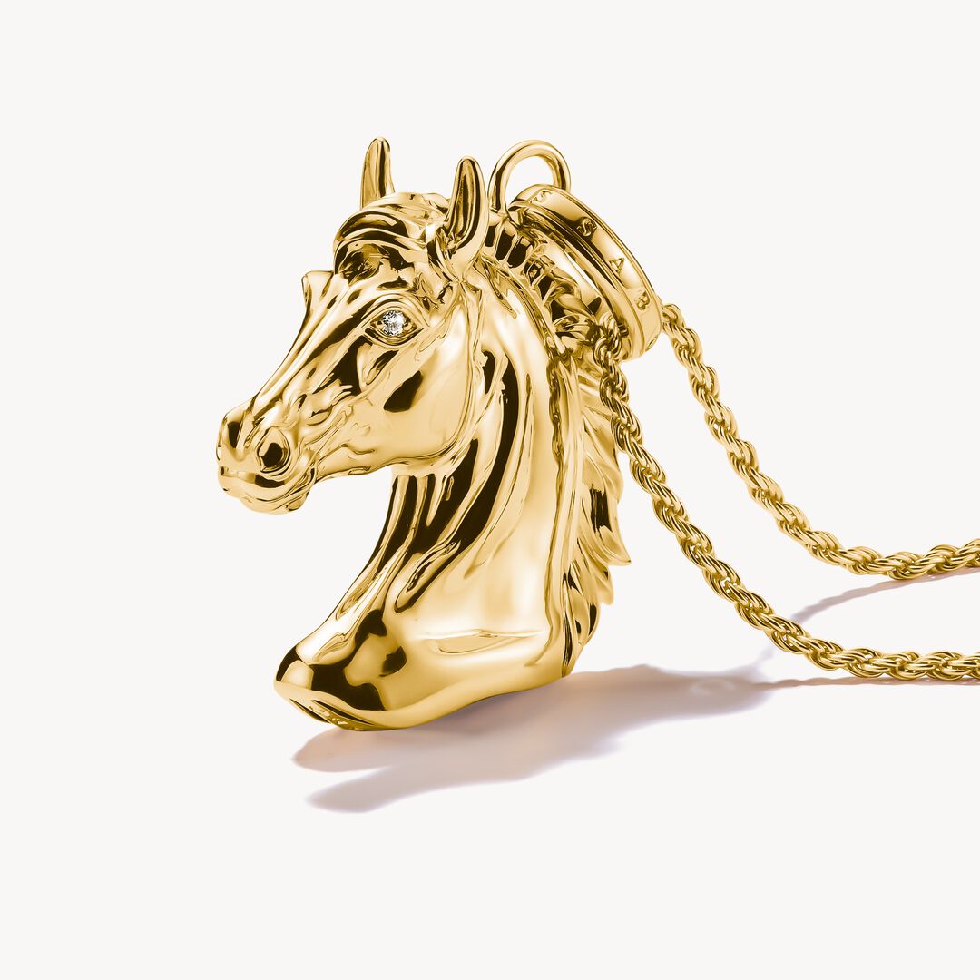 Gold horse head pendant on a gold chain against a white background