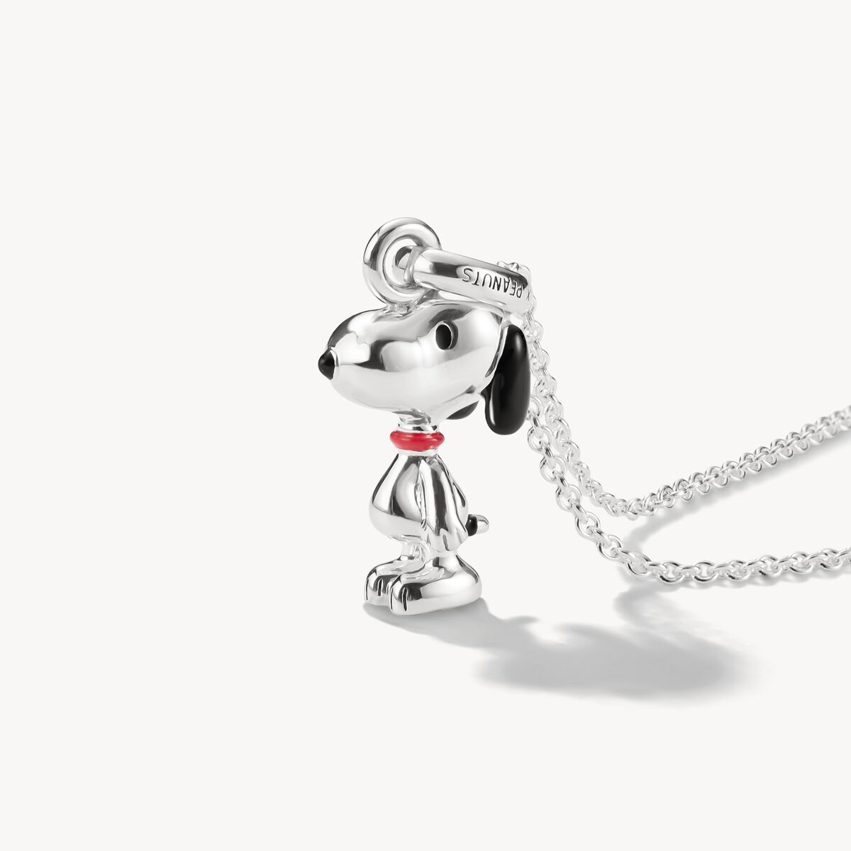 Silver dog-shaped pendant on a chain against a white background