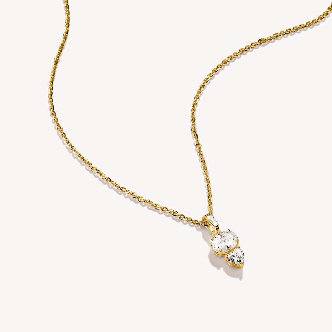 Gold necklace with a three-stone heart-shaped diamond pendant on a white background