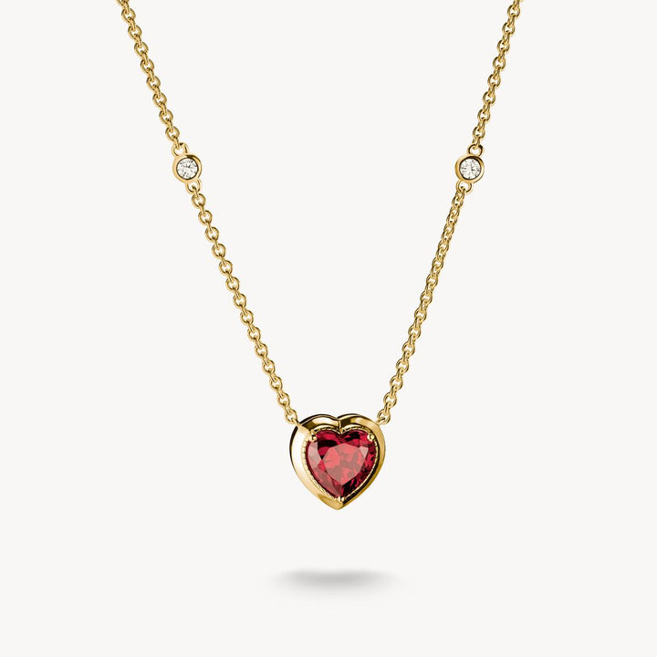 Gold necklace with a heart-shaped red gemstone pendant on a white background