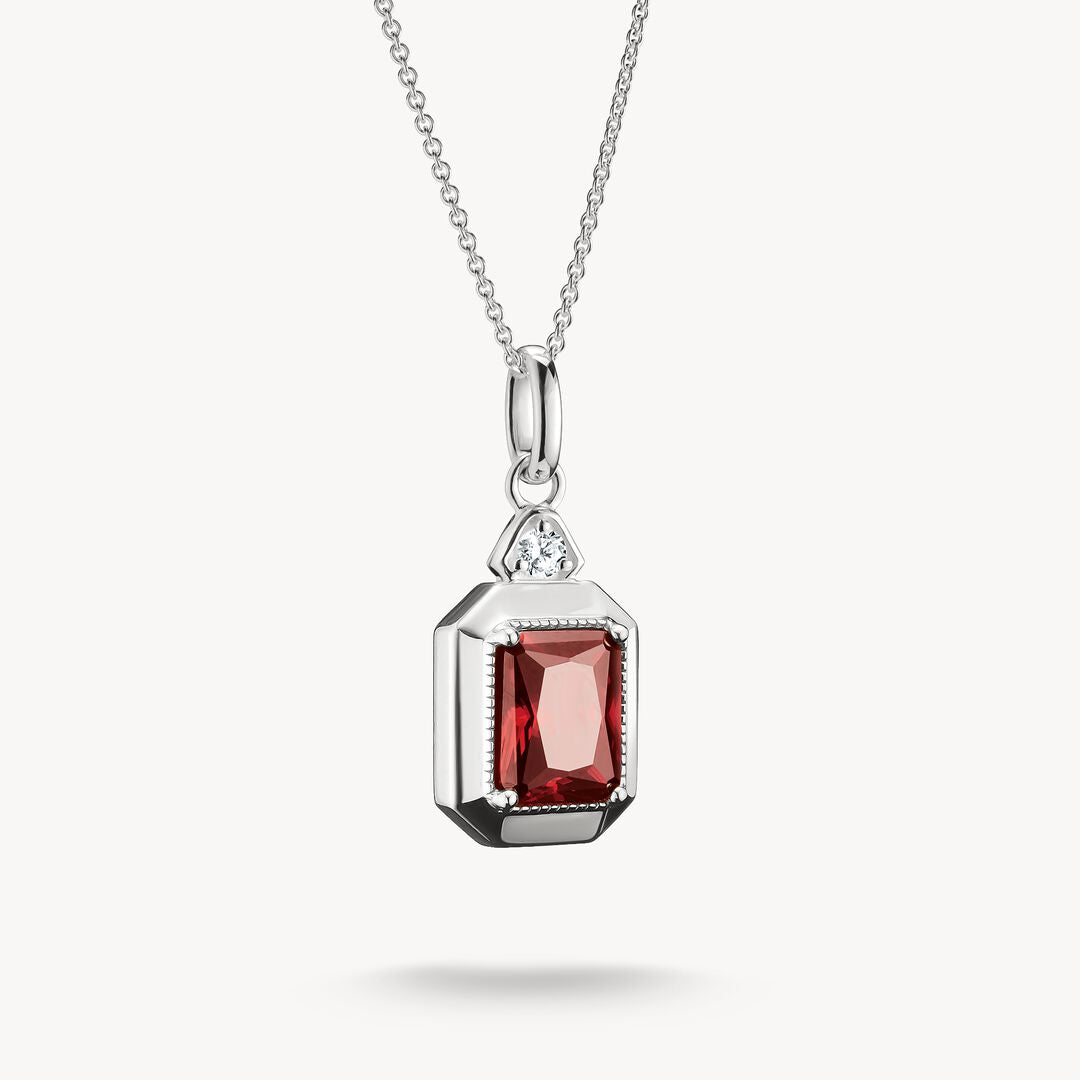 Silver pendant with a red gemstone on a white background