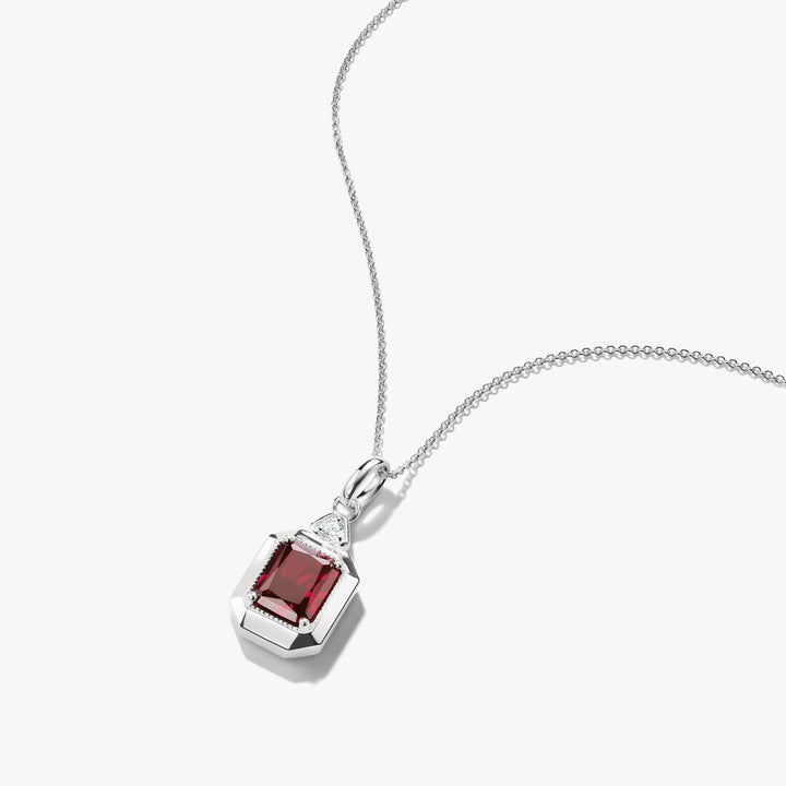 Silver necklace with a red gemstone pendant on a white background