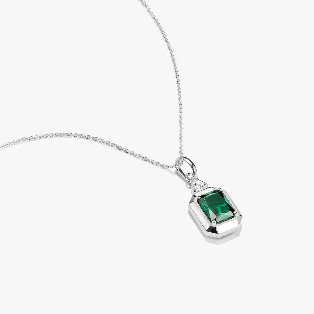 Silver pendant with green gemstone on a white background