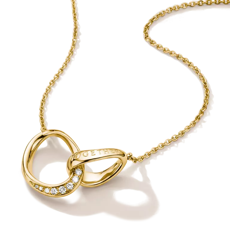 A gold necklace featuring an open interlocking ring pendant with a small row of clear stones on one side and a teardrop-shaped gold element on the other, shown on a white background.