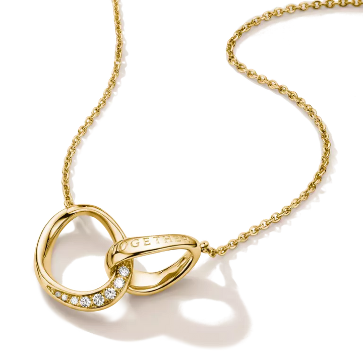 A gold necklace featuring an open interlocking ring pendant with a small row of clear stones on one side and a teardrop-shaped gold element on the other, shown on a white background.