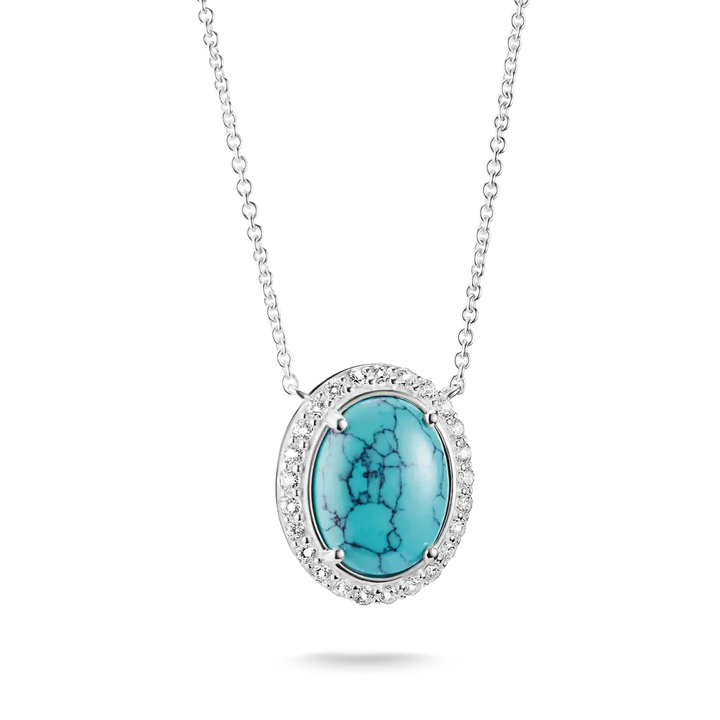 An oval pendant necklace featuring a vibrant turquoise stone with black matrix veining, surrounded by a halo of small clear stones and set in silver-toned metal, suspended from a delicate silver chain against a white background.