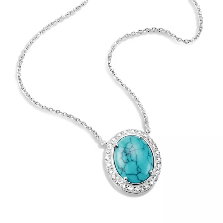 Silver oval pendant necklace featuring a turquoise-colored stone with black matrix veining, surrounded by a halo of small clear stones on a white background.