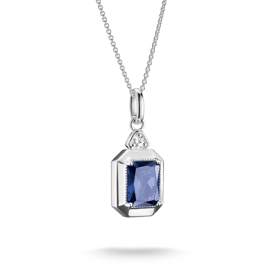 A silver pendant necklace featuring a rectangular blue sapphire gemstone in a silver bezel setting, with a small clear accent stone above it, shown on a white background.