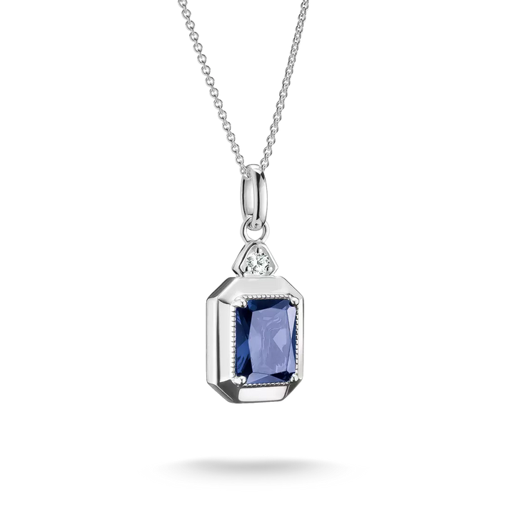 A silver pendant necklace featuring a rectangular blue sapphire gemstone in a silver bezel setting, with a small clear accent stone above it, shown on a white background.