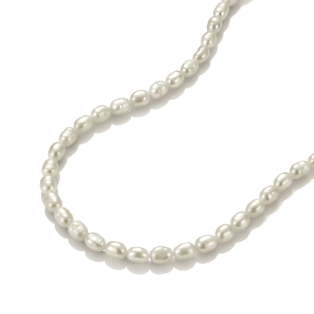 A strand of irregular white freshwater pearls arranged in a curved line on a clean white background.