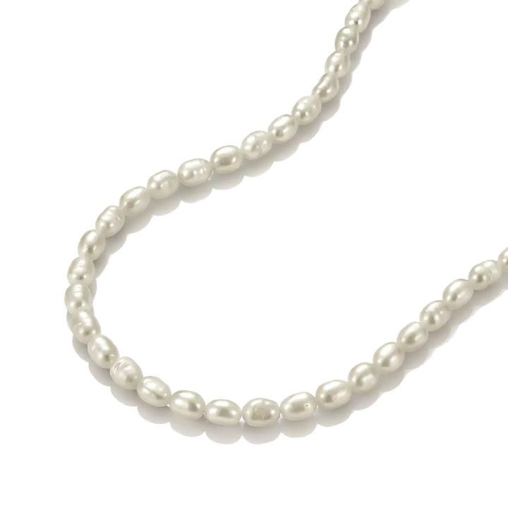 A strand of irregular white freshwater pearls arranged in a curved line on a clean white background.