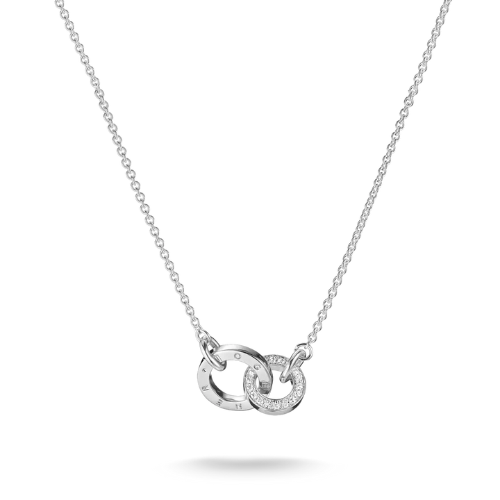 A silver chain necklace featuring two interlocking circular pendant elements, one with engraved Roman numerals and the other set with small clear stones, shown on a white background.