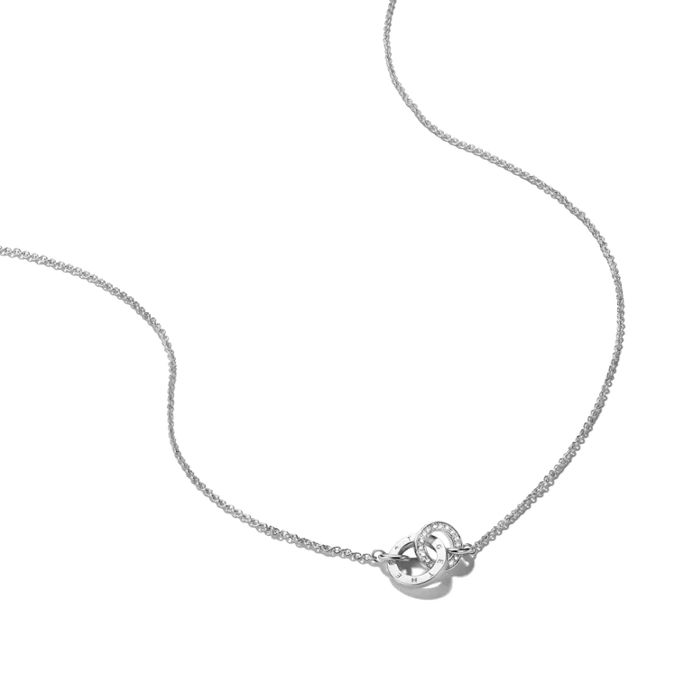 A delicate silver chain necklace featuring a small heart-shaped pendant with a clear central gemstone and a tiny round accent stone, shown on a plain white background.
