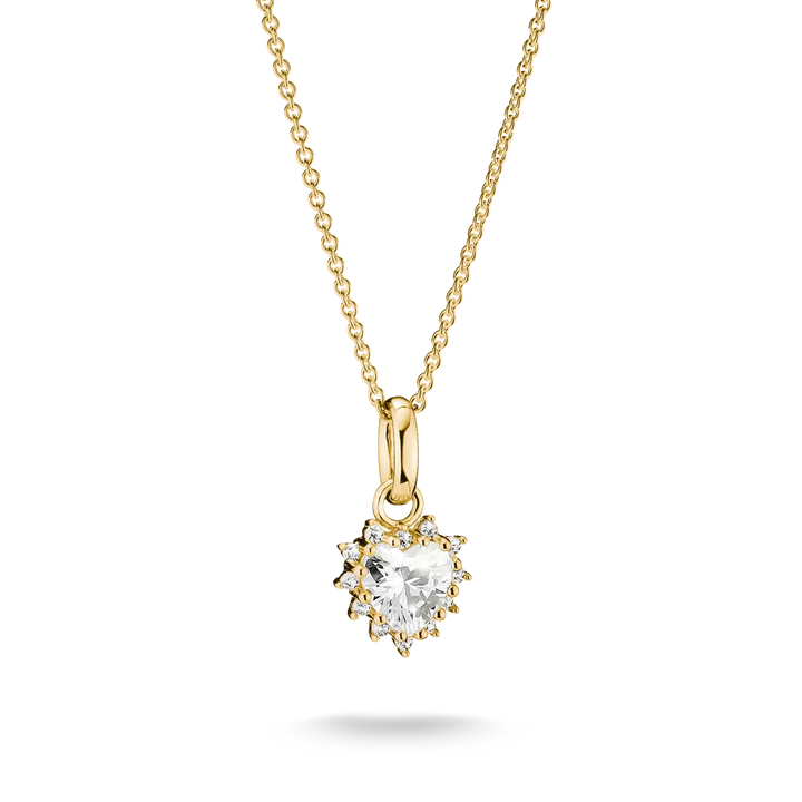 A yellow gold necklace with a heart-shaped clear gemstone pendant in a prong setting, suspended from a delicate gold chain against a white background.