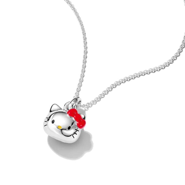 A silver pendant necklace featuring a Hello Kitty face with a red bow and small yellow nose, suspended on a silver chain against a white background.