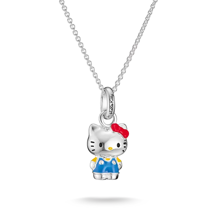 A silver Hello Kitty pendant necklace featuring a detailed character charm with blue overalls, yellow shoes, and a red bow, suspended from a delicate silver chain against a white background.