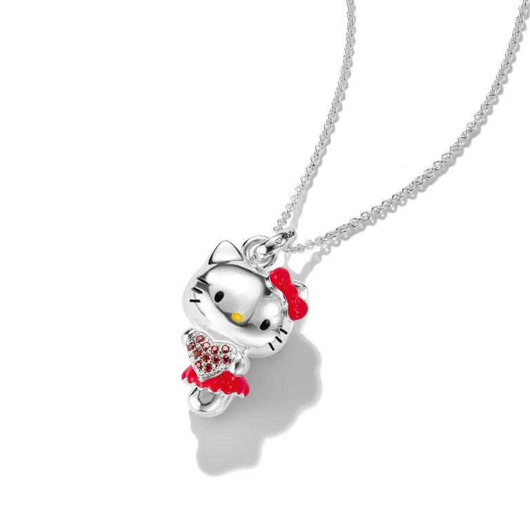 A silver Hello Kitty pendant necklace featuring a silver Hello Kitty figure with a red bow, red dress, and a red heart-shaped crystal heart, suspended on a silver chain against a white background.
