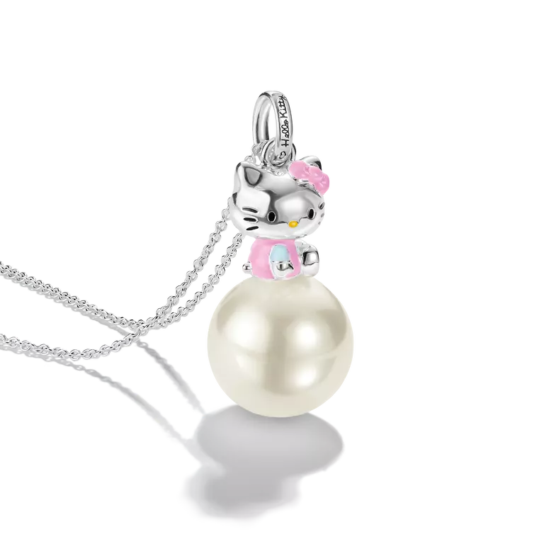 A silver pendant necklace featuring a Hello Kitty figure perched on a large white pearl. The pendant includes a silver bail with small clear stones, and the necklace is displayed on a clean white background with a soft reflection.