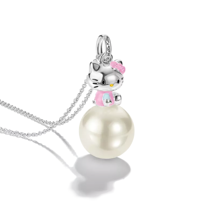 A silver pendant necklace featuring a Hello Kitty figure perched on a large white pearl. The pendant includes a silver bail with small clear stones, and the necklace is displayed on a clean white background with a soft reflection.