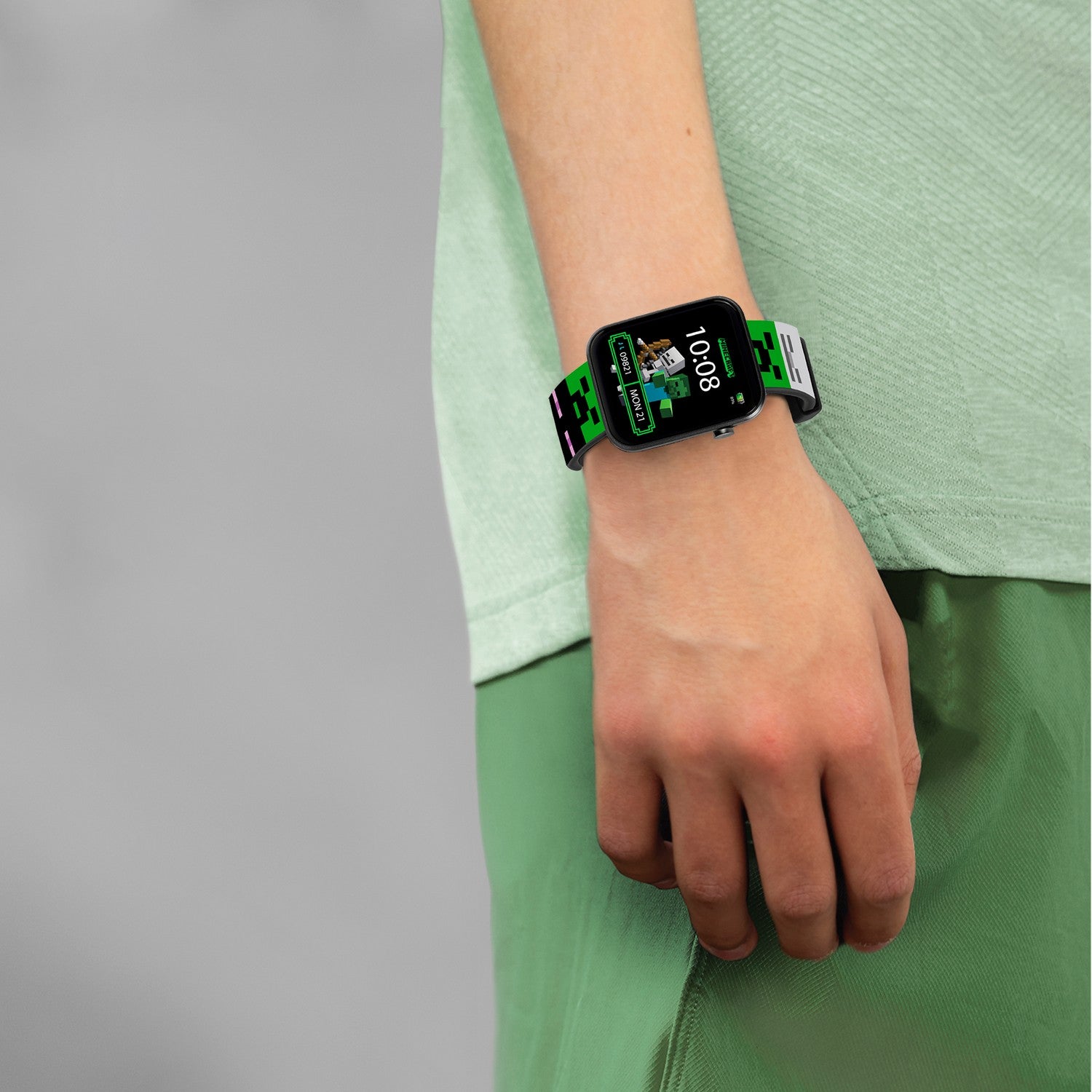 Person wearing a smartwatch with a green strap on a plain background