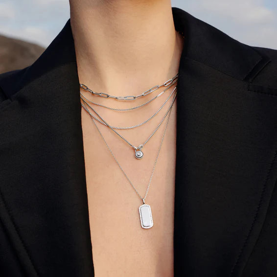 Person wearing multiple silver necklaces with a black blazer