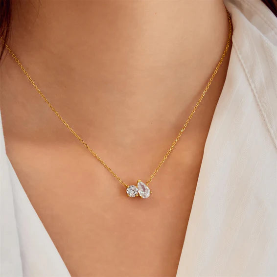 Gold necklace with a pendant on a person wearing a white top