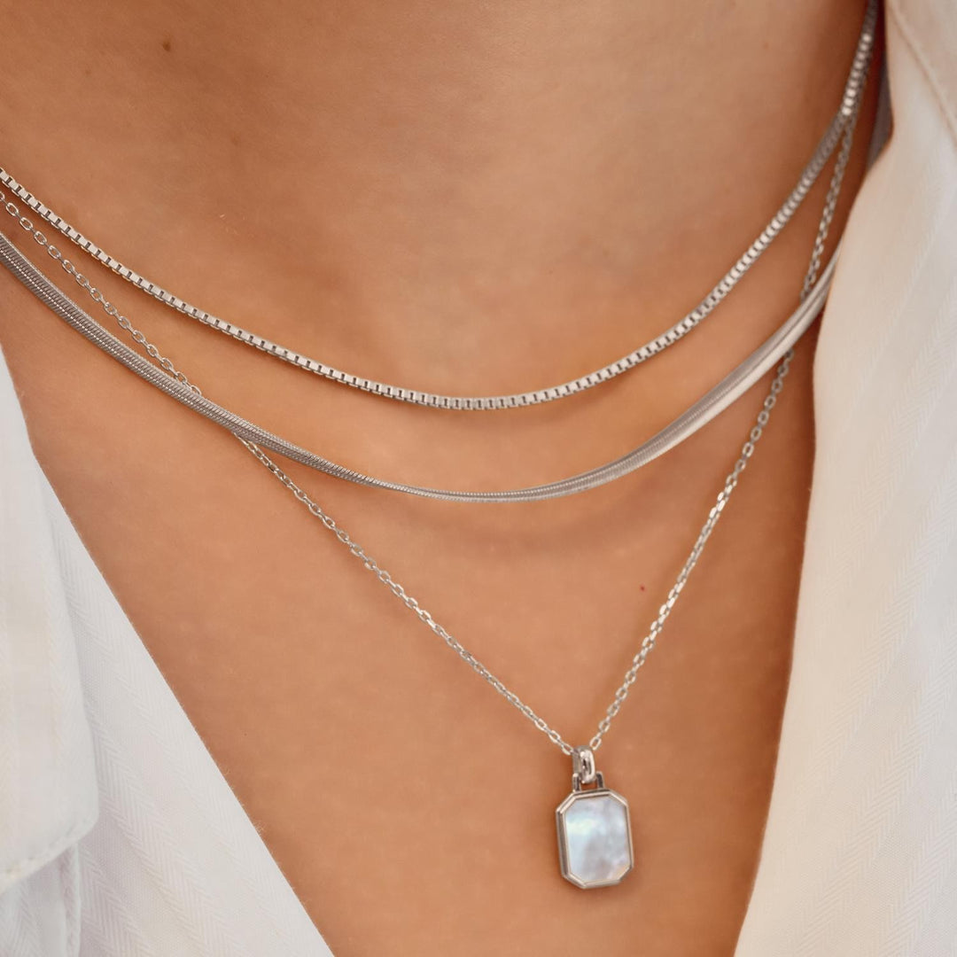 Silver necklace with a pendant on a person's neck