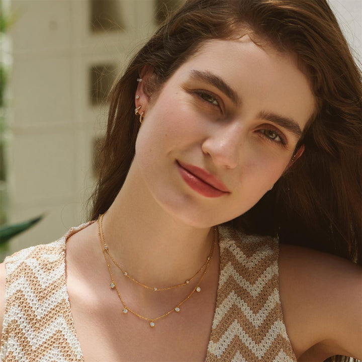 Woman wearing a gold necklace with a blurred background