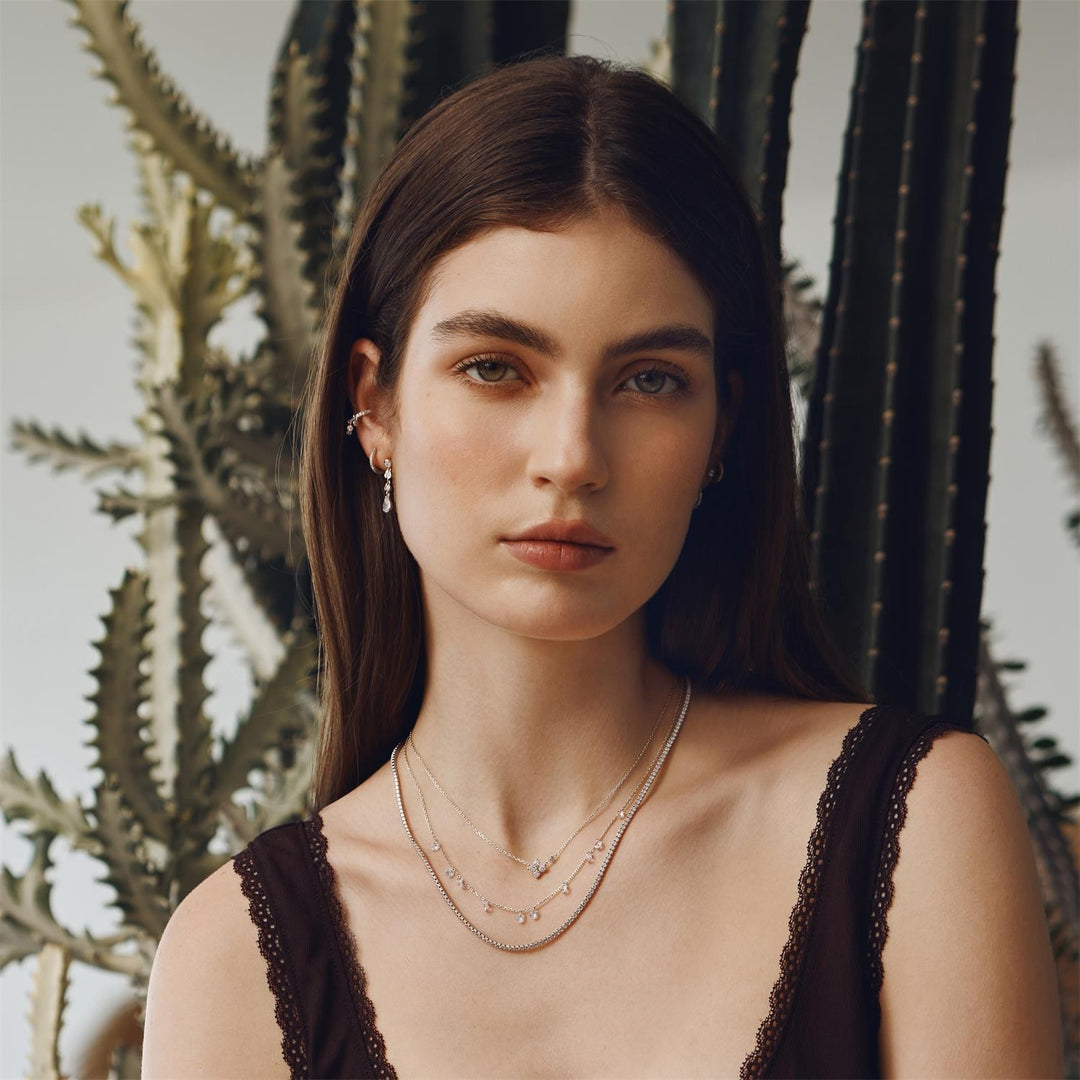 Woman wearing layered necklaces in front of cacti