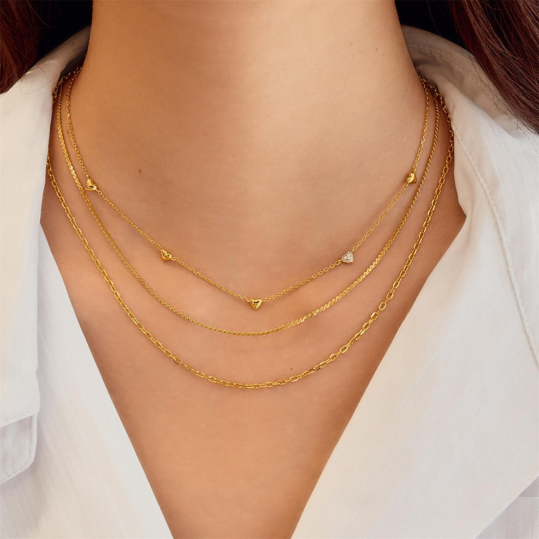 Gold necklaces on a person wearing a white shirt