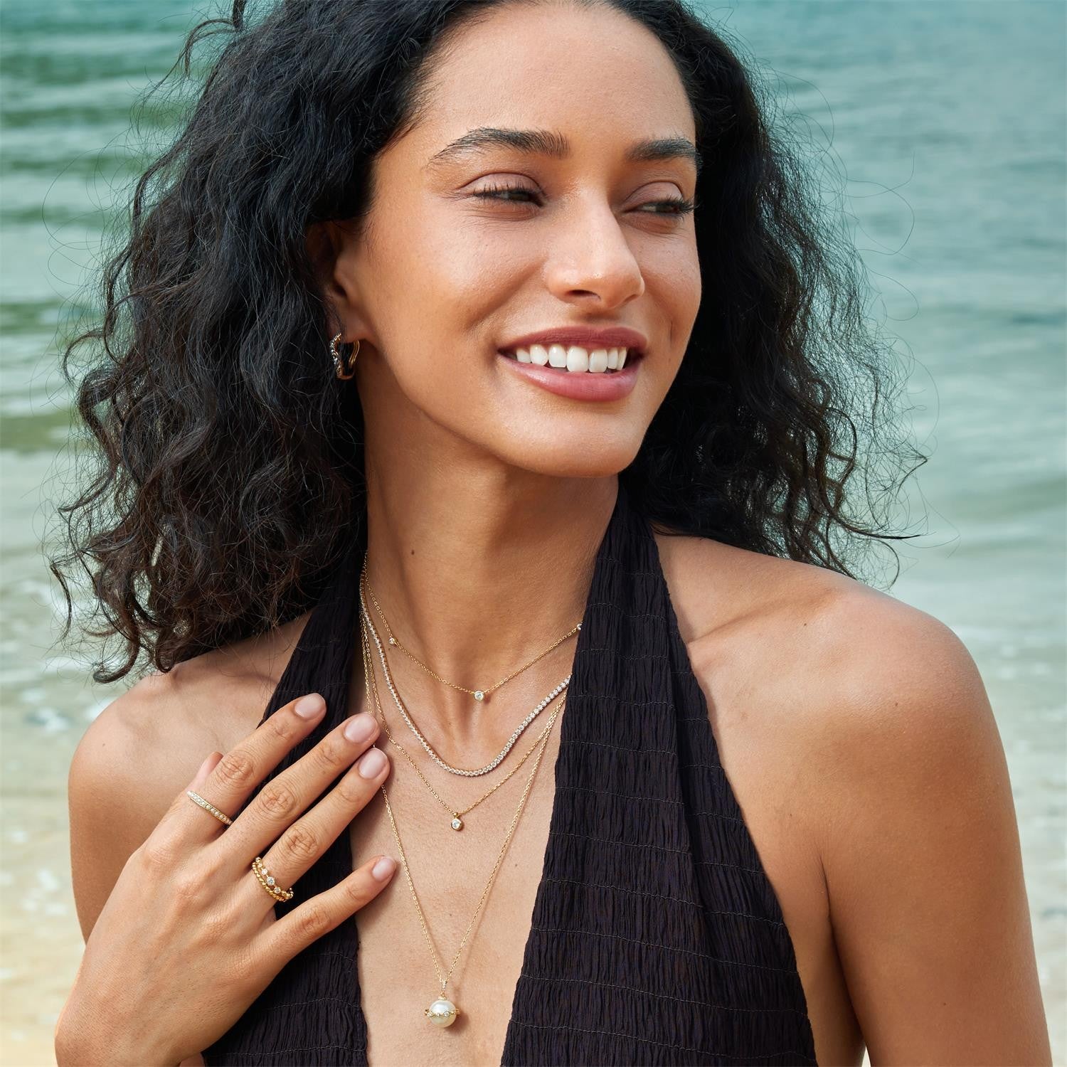 Woman with layered necklaces and a ring on a beach
