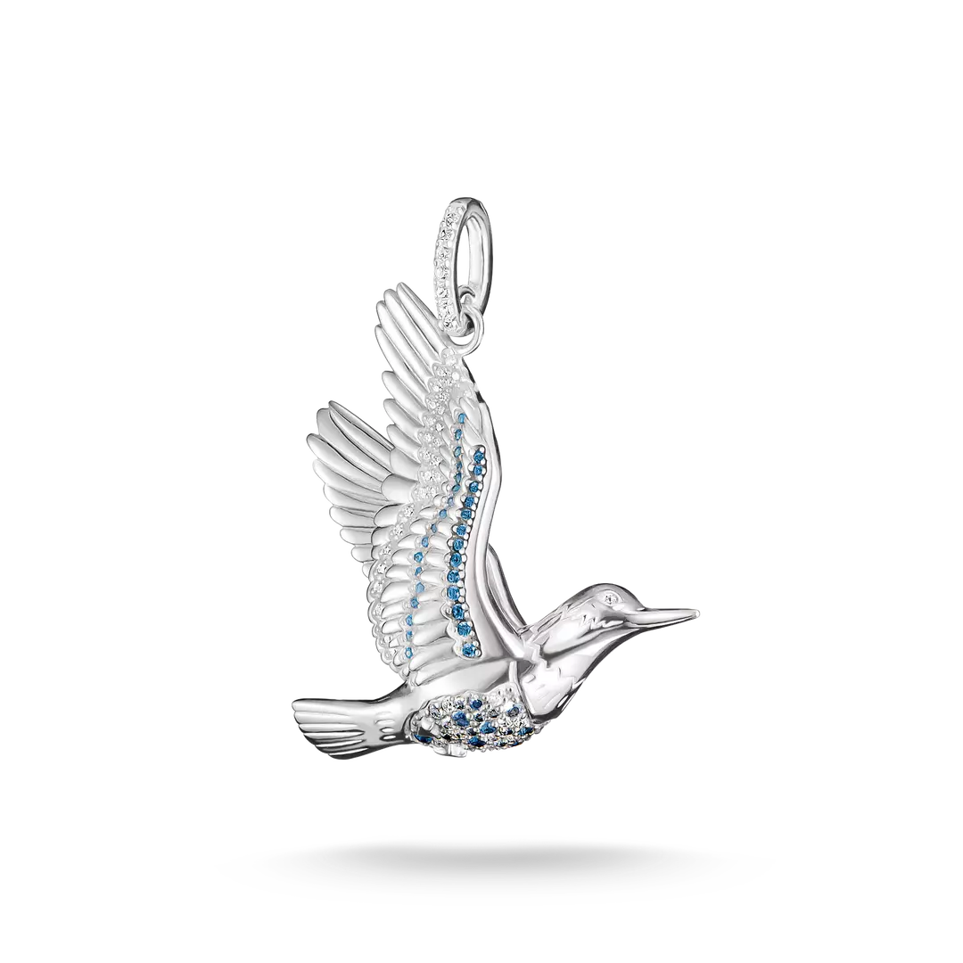A silver bird pendant in flight, embellished with small blue stones along its body and wing, shown on a clean white background with a soft shadow underneath.