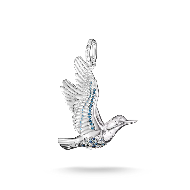 A silver bird pendant in flight, embellished with small blue stones along its body and wing, shown on a clean white background with a soft shadow underneath.