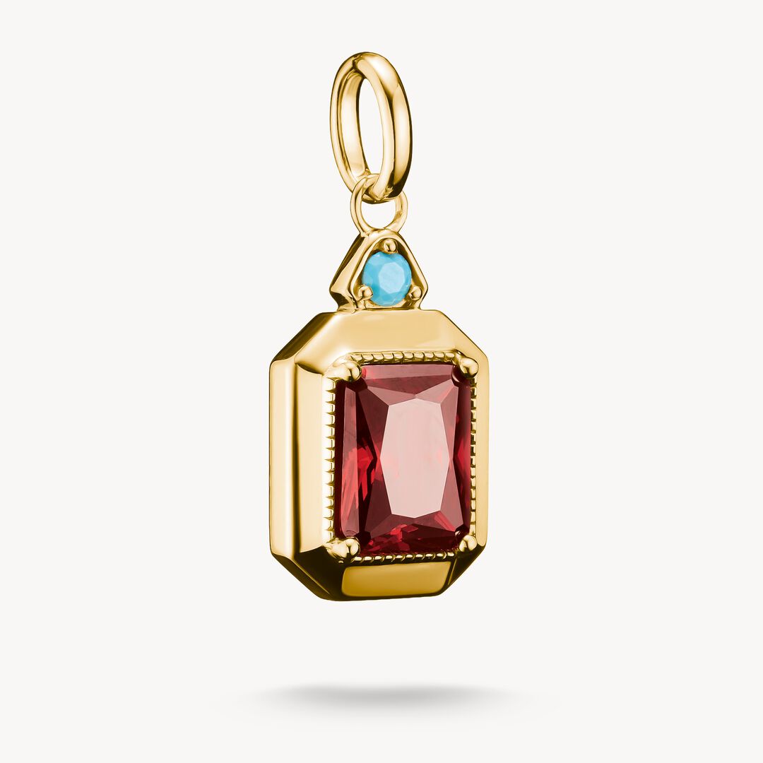 Gold pendant with red gemstone and blue gemstone on a white background