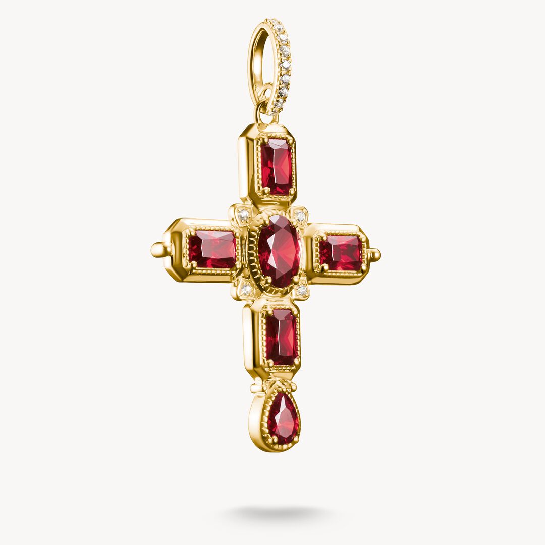 Gold cross pendant with red gemstones on a white background