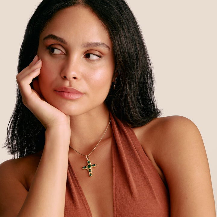 Woman wearing a necklace with a cross pendant on a beige background
