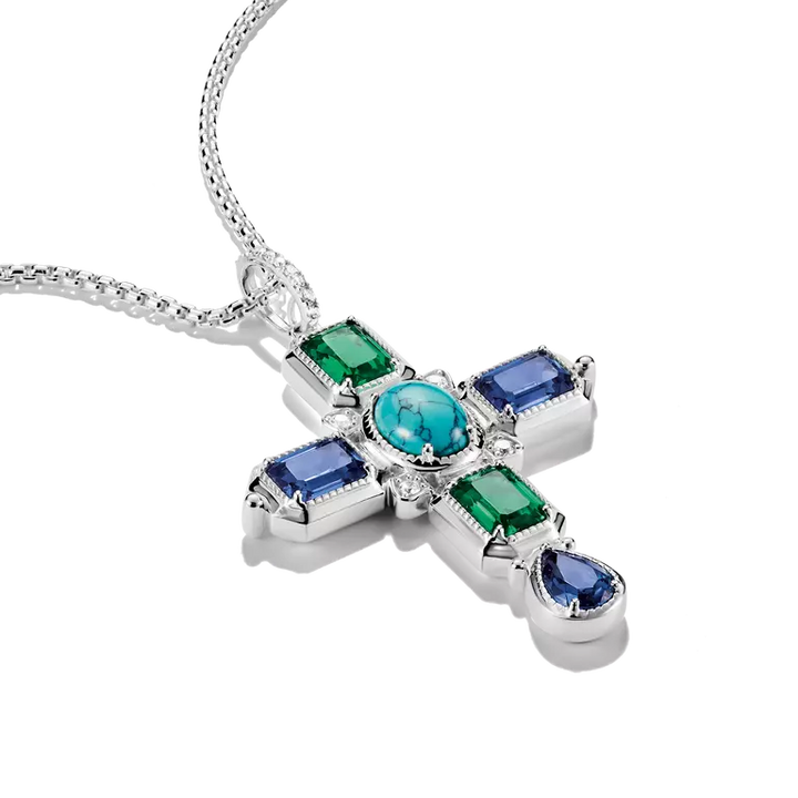 A sterling silver cross pendant necklace featuring a central round turquoise gemstone surrounded by emerald-cut green and rectangular blue gemstones, with a teardrop-shaped blue gemstone at the bottom, shown on a white background.