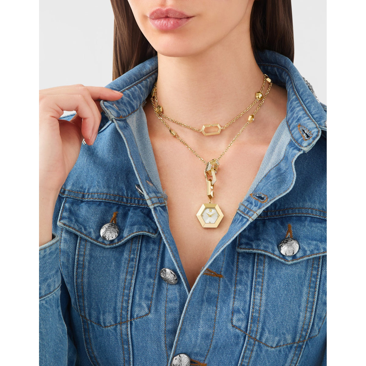 Woman wearing a gold necklace with a hexagonal pendant against a neutral background