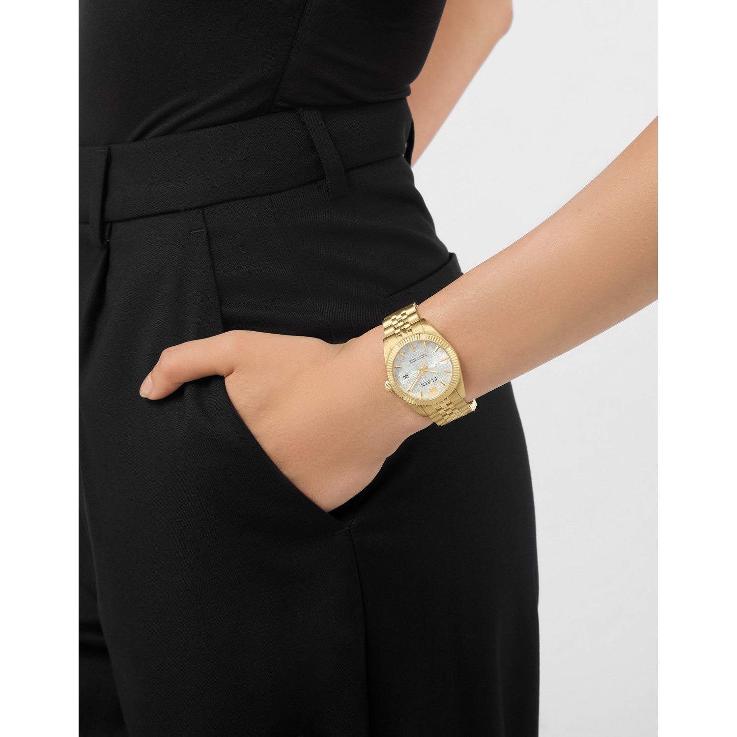 Gold watch on a wrist with a plain background