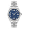 A silver-tone stainless steel wrist watch with a fluted bezel, a blue textured dial, Roman numeral hour markers, crystal hour indices, and a three-link metal bracelet, shown against a plain white background.